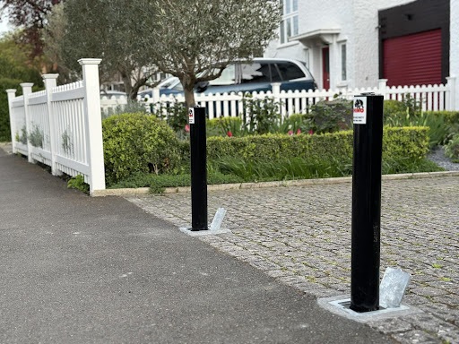 Two security bollards outside private house and driveway with fence in the background