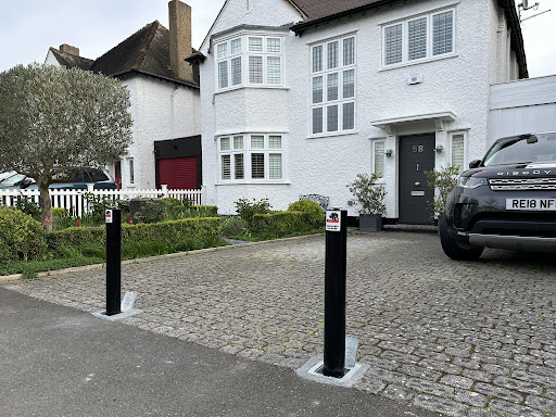 Two security bollards outside large white private house and driveway