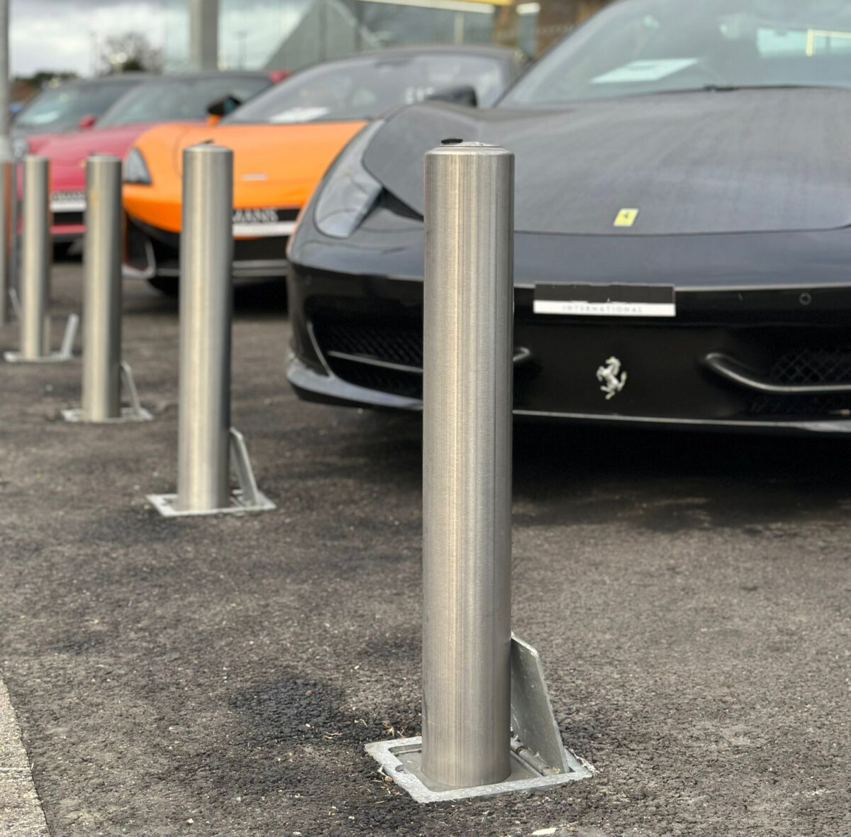 A line of steel bollards in front of luxury cars